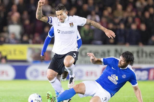 Posh star Michael Bostwick tackles Cobblers striker Marc Richards.