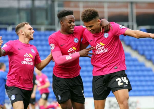 Lee Angol (right) celebrates his second goal at Oldham last season with the help of Jon Taylor (left) and Jermaine Anderson. Photo: Joe Dent/theposh.com.