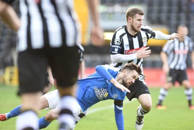 Posh goalscorer Gwion Edwards goes down under a Notts County challenge. Photo: David Lowndes.