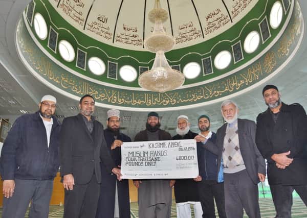 Faizan-e-Madina Peterborough Mosque Chairman Abdul  Choudhuri presenting a cheque on behalf of members of the mosque to Taukir Iqbal  from Muslim Hands  for the Kashmir Appeal EMN-160612-153357009