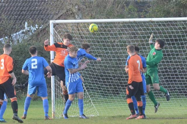 George Edwards of Thorney (orange) attacks a cross in the Peterborough Premier Division game against Pinchbeck. Photo: David Lowndes.