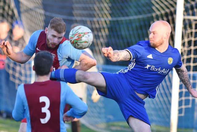Lewis Webb (blue) in high-kicking action for Peterborough Sports against Deeping Rangers. Photo: David Lowndes.