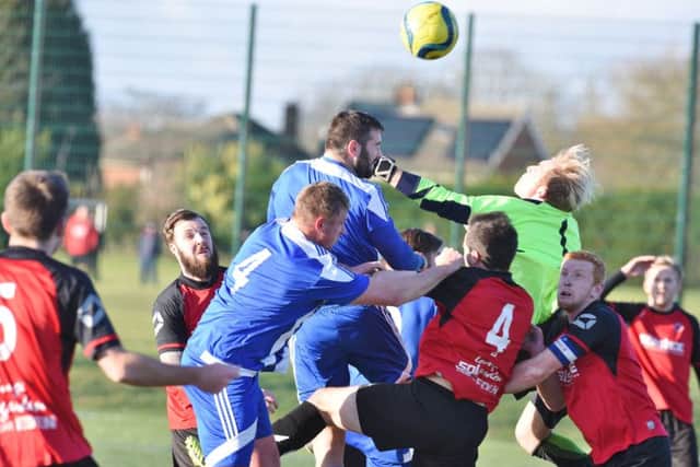 Netherton goalkeeper Ross Ingram looks like he's punching Peterborough Sports reserve team defender Carl Bird in the face in this picture by David Lowndes.