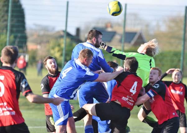 Netherton goalkeeper Ross Ingram looks like he's punching Peterborough Sports reserve team defender Carl Bird in the face in this picture by David Lowndes.