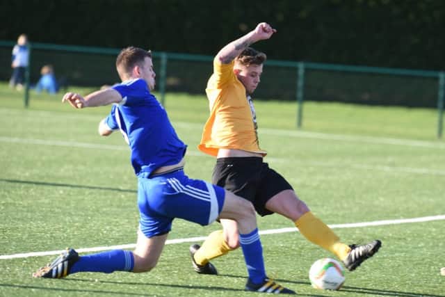 Debutant James Hill-Seekings (blue) in action for Yaxley against Harborough. Photo: David Lowndes.