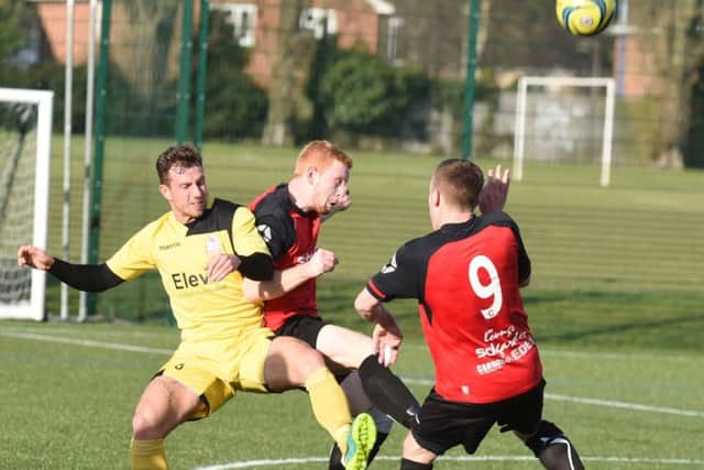 Netherton United skipper Herbie Panting (centre, red) in the thick of the action against Raunds. Photo: David Lowndes.