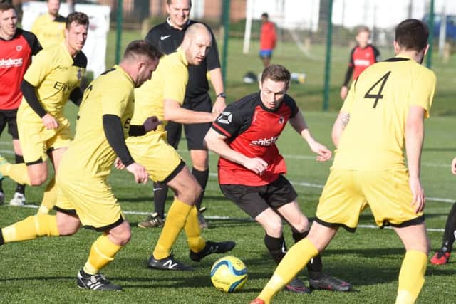 Netherton United's Tom Randall (red) is surrounded by Raunds Town players. Photo: David Lowndes.