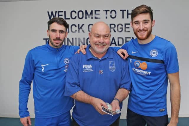 Posh players Michael Smith (left) and Jack Baldwin (right) hand over a donation to the Chris Turner Statue Fund to Adi Mowles.