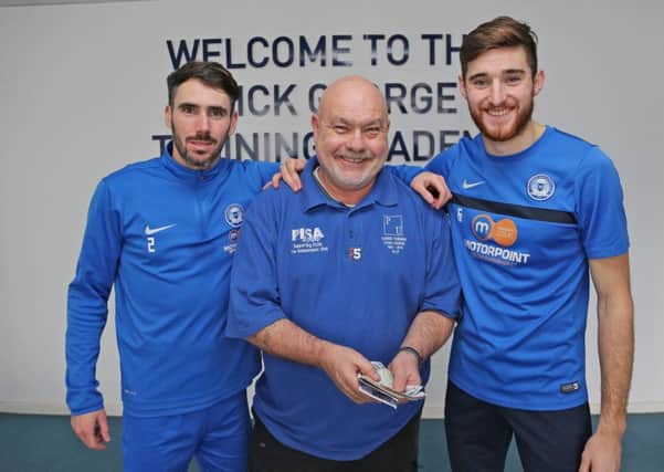 Posh players Michael Smith (left) and Jack Baldwin (right) hand over a donation to the Chris Turner Statue Fund to Adi Mowles.
