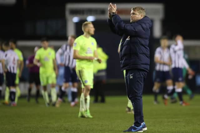 Posh manager Grant McCann applauds the travelling fans at Millwall.