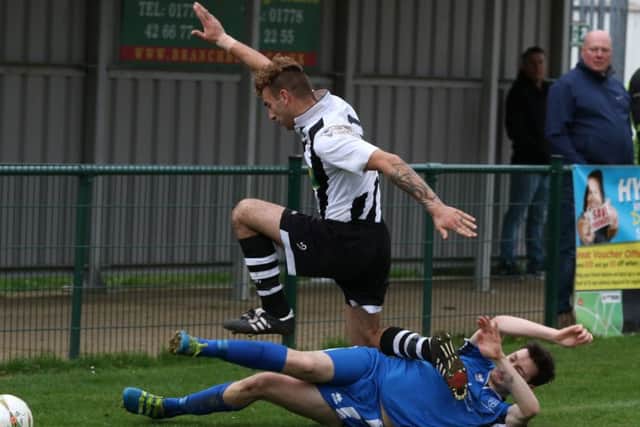 Jake Mason (stripes) of Peterborough Northern Star hurdles a challenge in the game against Cogenhoe. Photo: Tim Gates.