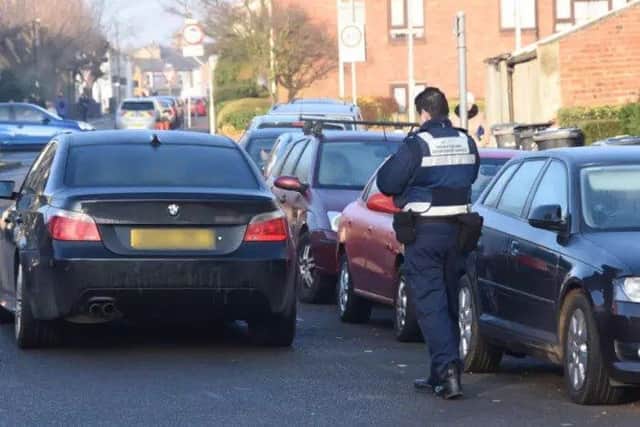 A car parked in the middle of the road outside Queen's Drive Infant School