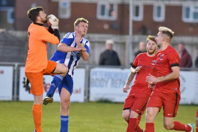 Karl Gibbs (blue) of Peterborough Sports Reserves challenges the Pinchbeck goalkeeper;. Photo: David Lowndes.