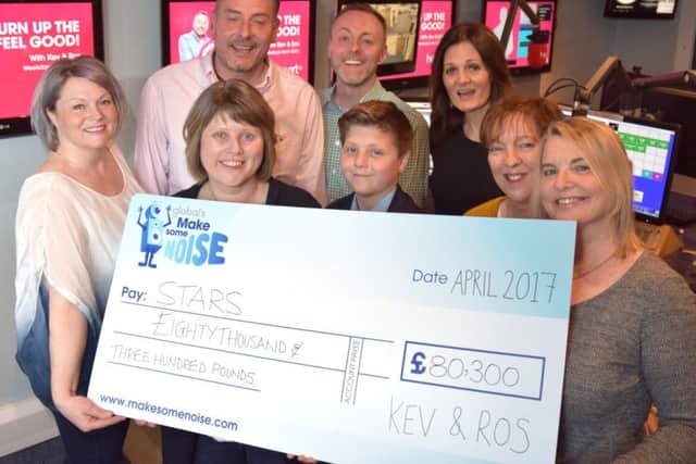 Heart Breakfast presenters Kev and Ros hand over a cheque from Globals Make Some Noise to parents and staff from STARS in Cambridgeshire.