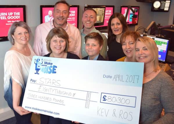 Heart Breakfast presenters Kev and Ros hand over a cheque from Globals Make Some Noise to parents and staff from STARS in Cambridgeshire.