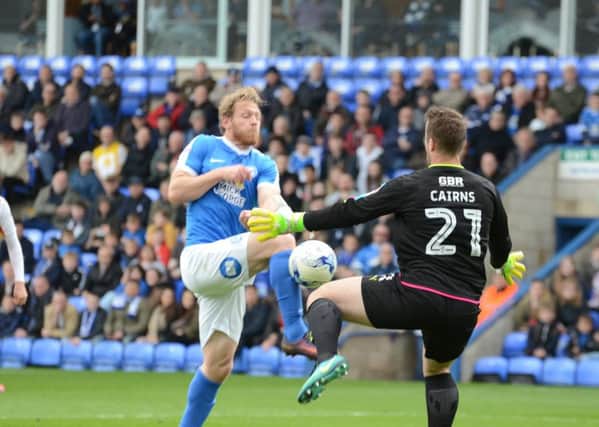 Posh striker Craig Mackail-Smith is about to be clattered by Fleetwood goalkeeper Alex Cairns. Photo: David Lowndes.