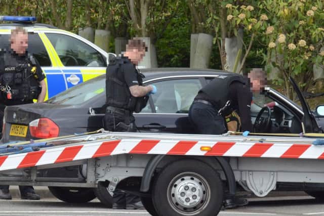 Armed police with sniffer dogs searching the BMW