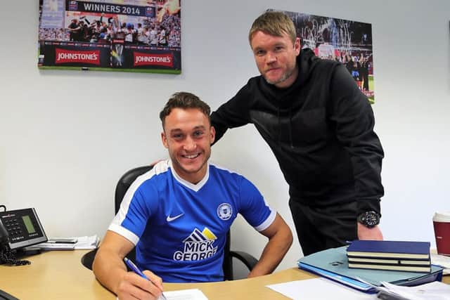 Ricky Miller signs for Posh watched by manager Grant McCann. Photo: Joe Dent/theposh.com.