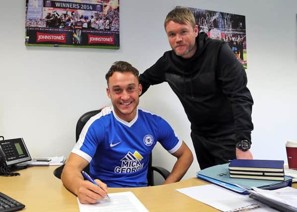 Ricky Miller signs for Posh watched by manager Grant McCann. Photo: Joe Dent/theposh.com.