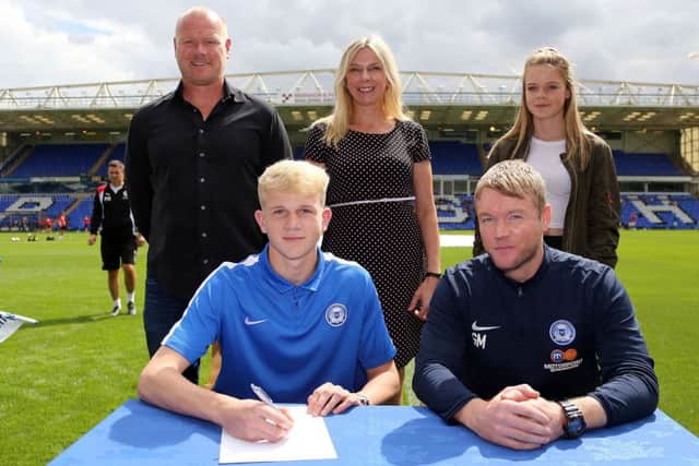 Lewis Freestone signs his three-year Posh contract alongside manager Grant McCann.