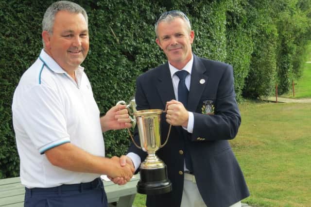 March handicap club champion  Gary Brinn receives his trophy from club captain Ivan Roberts.
