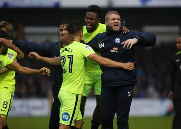 Posh manager Grant McCann celebrates a last-gasp winning goal with his players at Bristol Rovers last season.