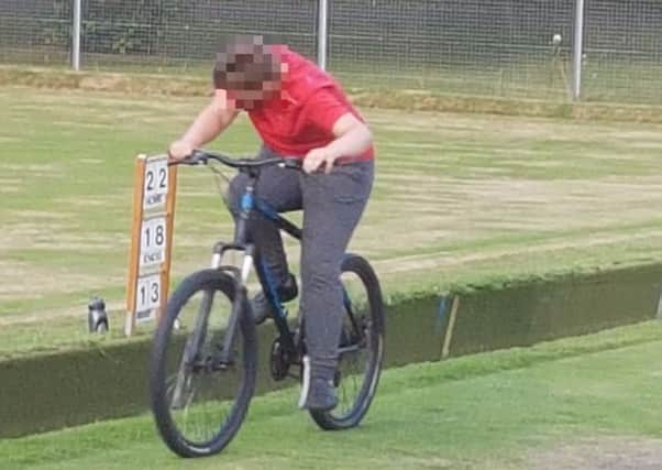 A youngster cycling on the bowling green pictured by one of the bowls players