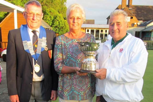 Janet Jaggard, daughter of the trophy donor, presents the Albert Rowlett Cup to Peterborough & District captain Jeff Clipston in the presence of Peterborough League president Bruce Saint.