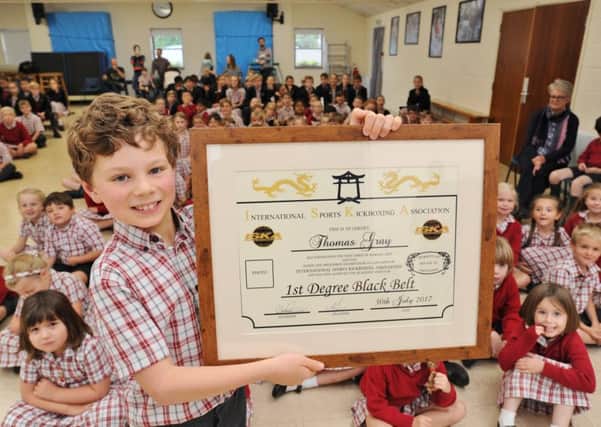 Thomas Gray proudly shows off his black belt certficate at his school assembly.