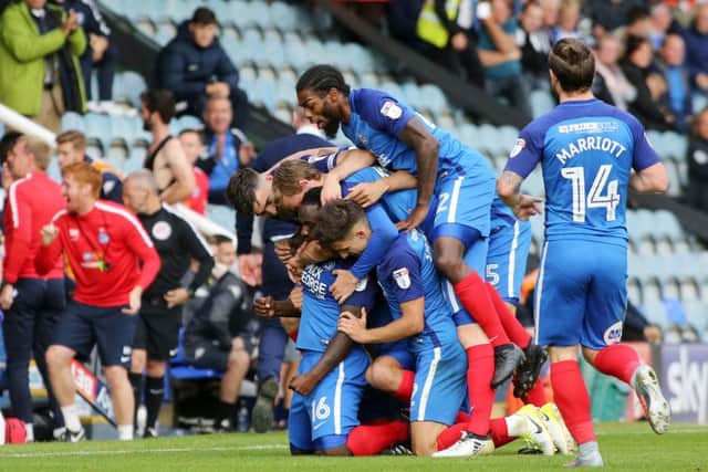 Junior Morias is mobbed by Posh team-mates after scoring his second goal against Wigan. Photo: Joe Dent/theposh.com.