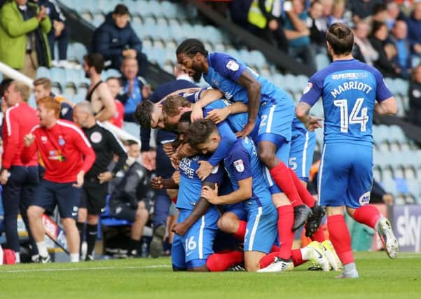 Junior Morias is mobbed by Posh team-mates after scoring his second goal against Wigan. Photo: Joe Dent/theposh.com.