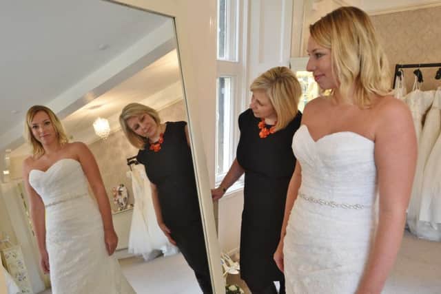 Business owners Rachael Cox and Laura Bailey, displaying one of the wedding gowns, at The Wedding Shop EMN-151117-162631009